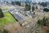 Aerial drone shot of property and surrounding area showing woodland with lots of trees, roads, gas station, and other local businesses and residential homes.
