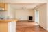 Main living area with fireplace, wooden floor, open plan kitchen, ceiling fan, and patio.