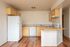 Open plan kitchen area with fridge, disherwasher, oven, stove, countertops, cupboards, and wooden floor.