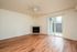 Living area with fireplace, wooden floors, ceiling fan, and patio.