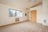 Main area with carpet, entrance, window, AC and heating unit, ceiling fan, and plasterer walls.