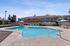Pool with lounge chairs, sun, bushes, and table and chair sets