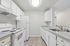 galley view of kitchen in C1 renovated floorplan at Timber Flats white cabinets white appliances and grey countertops