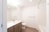 Bathroom at Orrin showing the shower, wood cabinets and flooring, white countertops