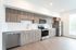 Orrin studio kitchen along one wall with white backsplash, wood cabinets, wood flooring and stainless steel appliances