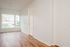 One Bedroom at Lyra Apartments - view into the living room with white walls, large window and hardwood floors