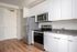 Kitchen and entryway at Lyra apartments with grey countertops and stainless steel appliances