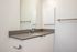 One Bedroom at Lyra Apartments - Bathroom with grey counter and mirror above the sinkfloors
