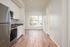 One Bedroom at Lyra Apartments - view from kitchen into the living room with stainless steel appliances and hardwood floors