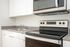 One-Bedroom at Lyra Apartments - closeup of kitchen with grey countertops and stainless steel appliances