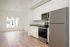 One-Bedroom at Lyra Apartments - view from the kitchen into the living room with stainless steel appliances and hardwood floors