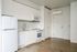 Cassi Apartments - kitchen with white appliances and white countertops and cabinets and view to the front door entryway