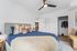 Bedroom at Orrin showing the bed, closet, ceiling fan with white walls and hardwood floors
