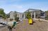 Playground with apartments, trees, sand, and blue sky.