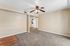 Living space with carpet, wooden floor, ceiling fan, and open space.