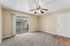 Living space with wooden floor, carpet, ceiling fan, and patio.