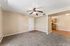 Open plan living area with carpet, wooden floor, ceiling fan, and kitchen.