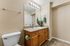 Bathroom with toilet, sink, mirror, wooden counter tops and cupboard.