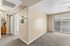 Open living area with carpet, patio, ceiling fan, AC unit, and hallway to bathroom.
