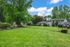 Field with trees, blue sky, and apartments.