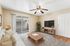 virtually staged living room with sofa, tv, coffee table, ceiling fan, and patio.
