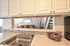 Stainless steel kitchen sink and white cabinets with a view of the stairs at CAMPBELL PARK.