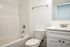 Bathroom with toilet, tub, sink, and mirror.