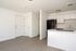 Open plan living and kitchen area with doors, wooden floors, counters, fridge, sink, and oven.