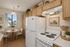 Virtually staged kitchen at Orchard mesa with a dining nook, white appliances, wood cabinets and white counter tops