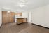 Living room and view into the kitchen at Orchard Mesa with wood floors, wood cabinets, white walls and a ceiling fan