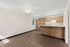 Living room and view into the kitchen at Orchard Mesa with wood floors, wood cabinets, white walls and a ceiling fan