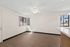 Living Room in a unit at Orchard Mesa with wood floors and white walls
