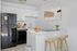 virtually staged kitchen with fridge, dishwasher, oven, stools, stink, and artwork.