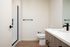 Bathroom at Cedarline with white countertops, wood cabinets and black finishes and glass shower door