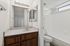Bathroom with wood cabinets and a separate room with a toilet and shower/tub combo