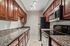 Kitchen at Solaris at The Biltmore with black/stainless appliances anf dark wood cabinets and tile flooring