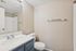 Bathroom vanity with a blue cabinet, white speckled countertop, and large wall mirror.