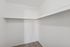 Walk-in closet with white walls and a built-in storage shelf and hanging rod.