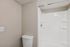 White walk-in shower with built-in shelving next to a white toilet.