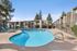 Kidney-shaped swimming pool surrounded by a fence and lounge seating.