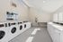 Bright laundry facility with rows of white front-loading washing machines.
