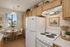 Virtually staged kitchen at Orchard mesa with a dining nook, white appliances, wood cabinets and white counter tops