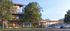 Modern apartment building with floor-to-ceiling windows, surrounded by lush trees, situated in a serene neighborhood. Stylish residents enjoying the view and bright, open spaces.