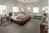 Elegant bedroom featuring a plush king-sized bed, modern decor, and ample natural light from multiple windows.
