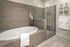 Luxurious bathroom featuring an elegant bathtub, modern glass shower, and stylish taupe tiles for a relaxing spa-like experience.