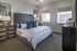 Elegant bedroom with a plush tufted headboard, soft bedding, and stylish decor accents, bathed in natural light from large windows.
