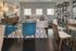 Elegant living room with modern furniture, featuring a plush corner sofa, stylish blue chairs, and a chic glass-top coffee table, complemented by a striking geometric bookshelf.