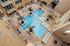 Luxurious aerial view of a modern apartment complex featuring a sparkling pool with elegant lounge areas and palm trees.