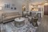 Elegant contemporary living room with plush beige sofa, stylish accent chairs, marble coffee table, and sleek open kitchen with bar seating.