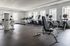 Modern fitness center with state-of-the-art gym equipment, including treadmills, stationary bikes, and strength training machines, offering panoramic city views through large windows.